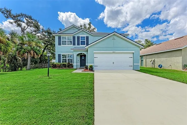 a view of a white house with a big yard and large trees