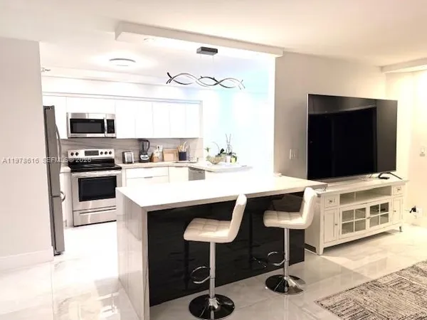 a kitchen with stainless steel appliances kitchen island granite countertop a refrigerator and a stove top oven