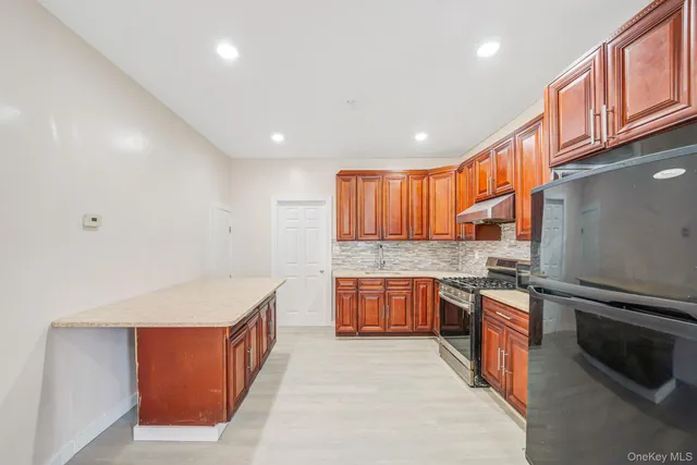 a kitchen with stainless steel appliances granite countertop a stove top oven a sink dishwasher a dining table and chairs with wooden floor