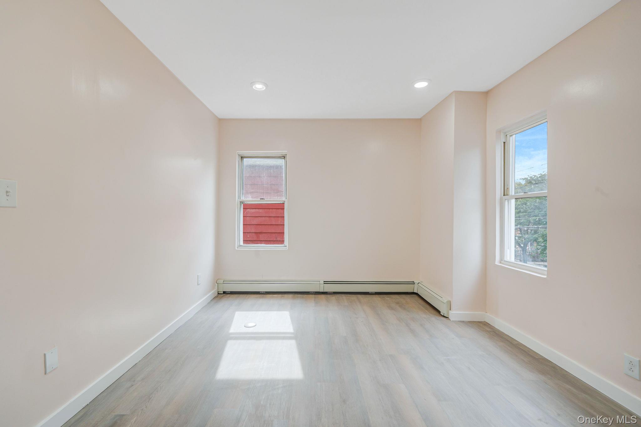 101-31 116th Street Queens, NY 11419 - Photo 7 of 19 an empty room with wooden floor and windows