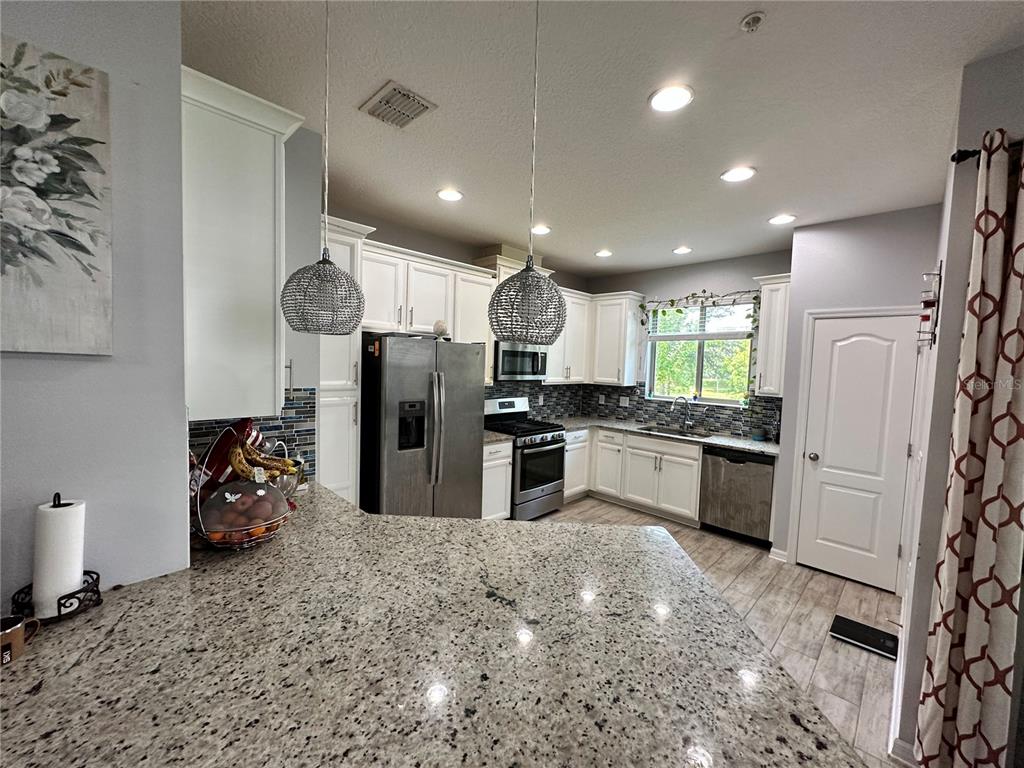 250 Rustic Loop Sanford, FL 32771 - Photo 4 of 33 a kitchen with stainless steel appliances kitchen island granite countertop a refrigerator and a sink