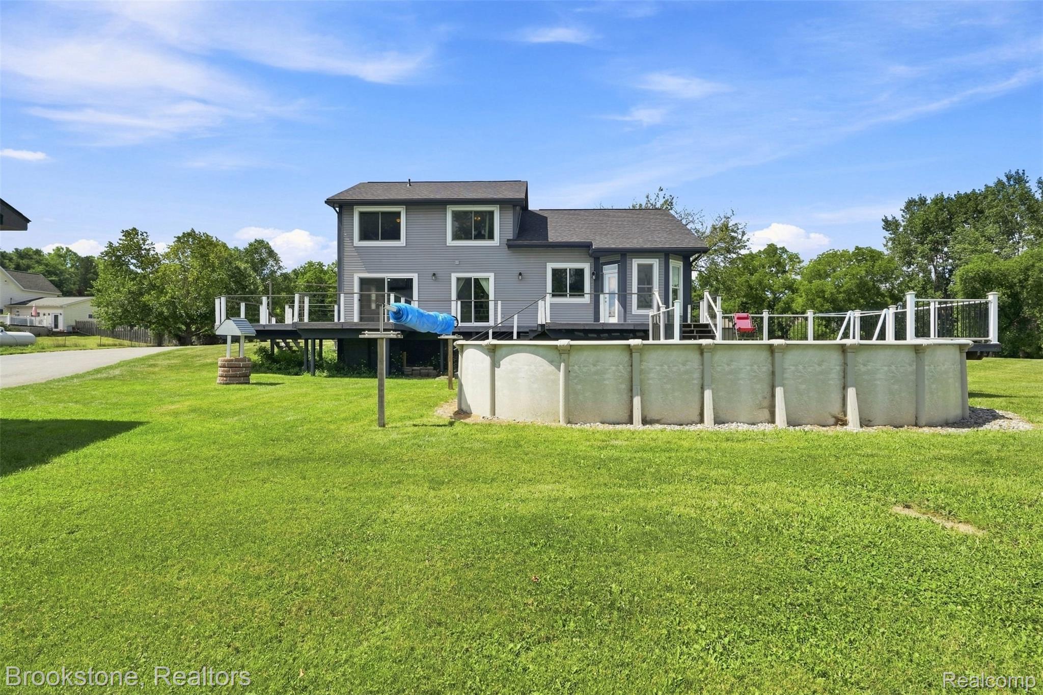 1775 Dutcher Road Howell, MI 48843 - Photo 30 of 41 Expansive backyard with a large above-ground pool, a spacious raised deck, and a manicured lawn