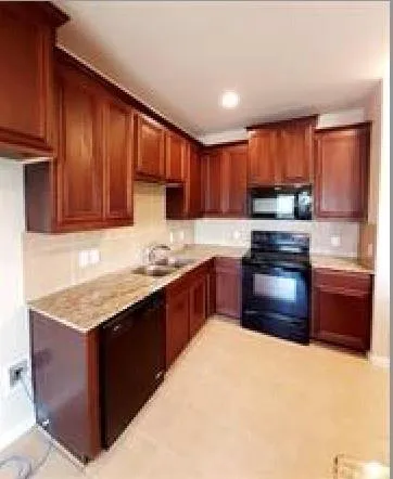 a kitchen with stainless steel appliances granite countertop wooden cabinets a stove top oven a sink and dishwasher with wooden floor