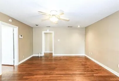 a view of an empty room with wooden floor and a window