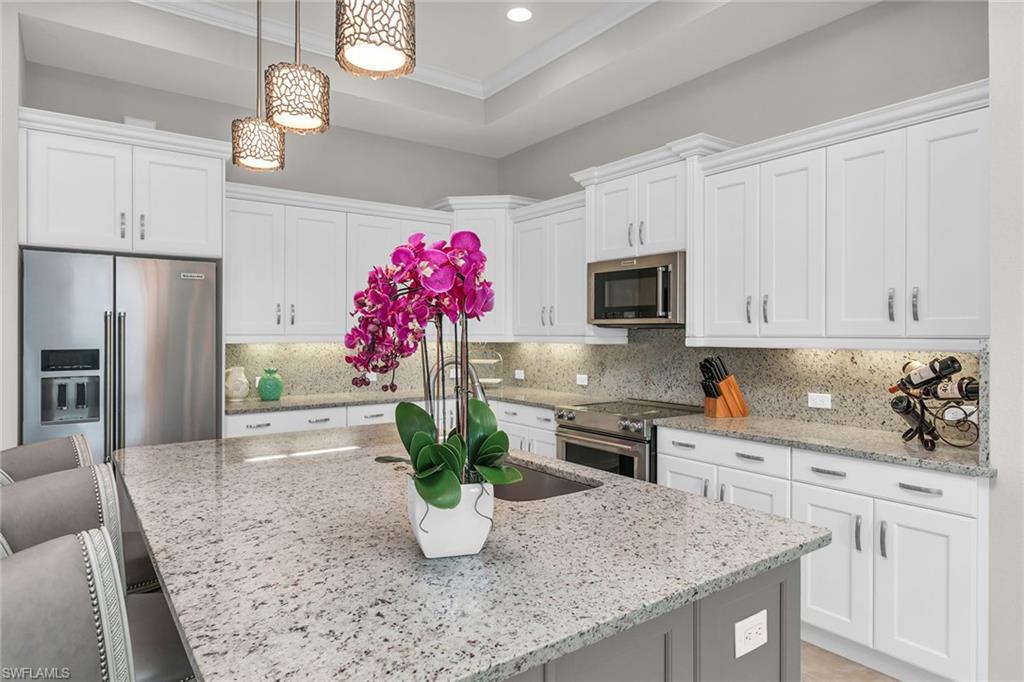 14812 Dockside Lane Naples, FL 34114 - Photo 4 of 49 a kitchen with stainless steel appliances granite countertop a dining table chairs cabinets a potted plant and a window