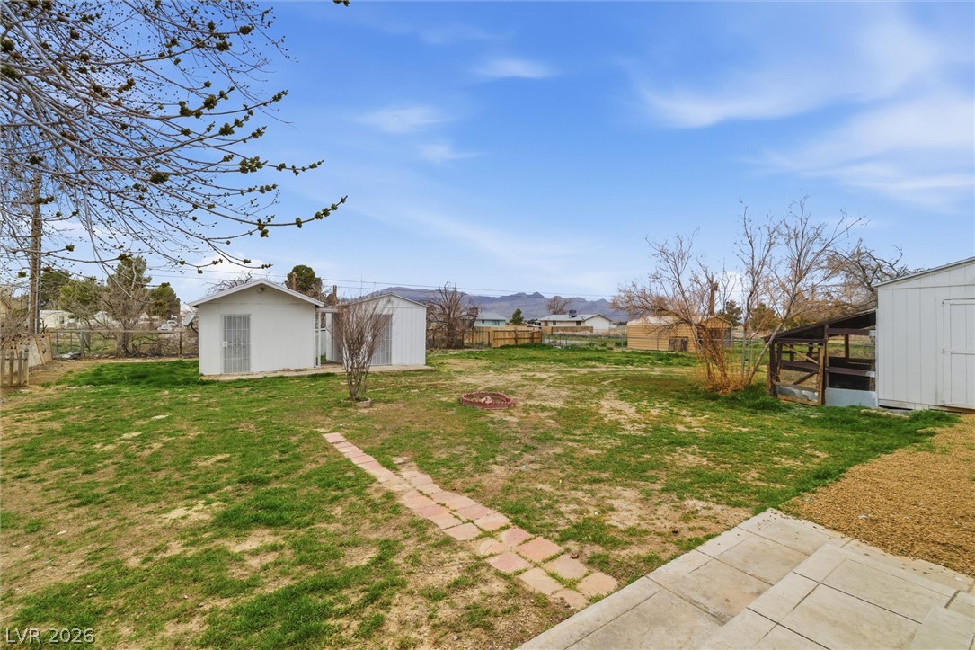 3940 Point Drive Pahrump, NV 89060 - Photo 31 of 35 A spacious backyard features two storage sheds, a charming stone path, and a distant mountain backdrop.