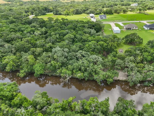 an aerial view of residential house with outdoor space and trees all around