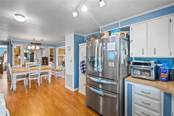 a kitchen with stainless steel appliances granite countertop a refrigerator a stove and a dining table with wooden floor