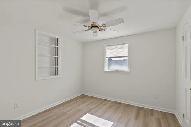 an empty room with a window and a ceiling fan