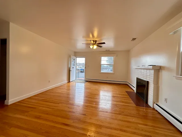 an empty room with wooden floor fireplace and windows