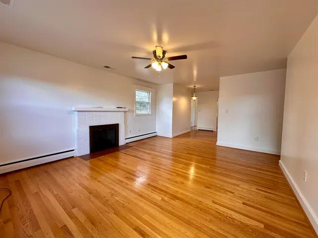 a view of an empty room with a fireplace and a chandelier fan