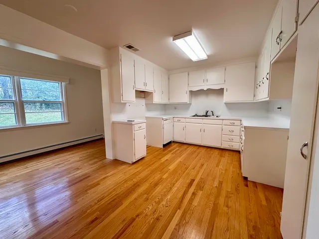 a large kitchen with wooden floors and stainless steel appliances