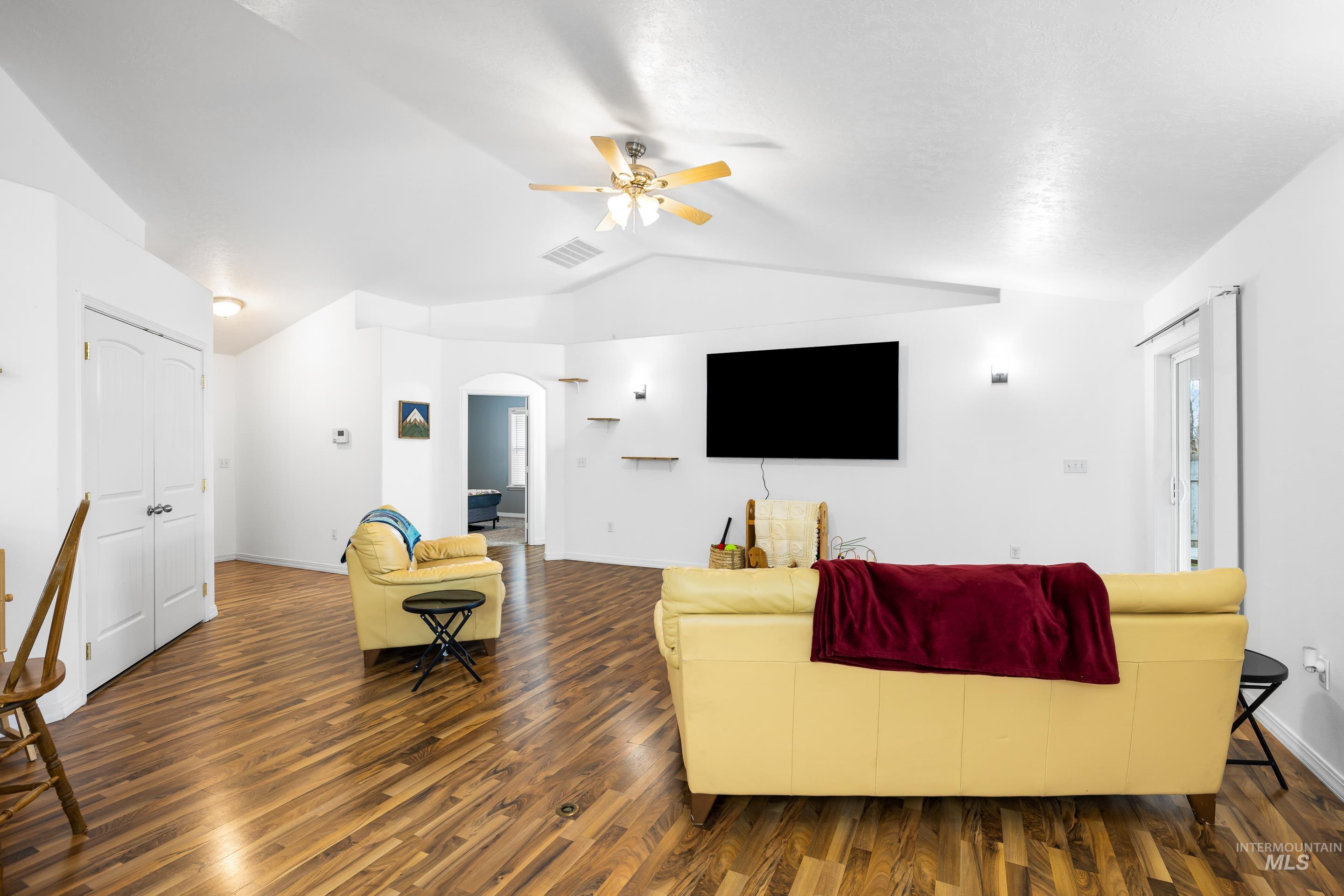 191 Southwest Quaker Drive Mountain Home, ID 83647 - Photo 11 of 43 Living area featuring arched walkways, dark wood-type flooring, ceiling fan, and vaulted ceiling