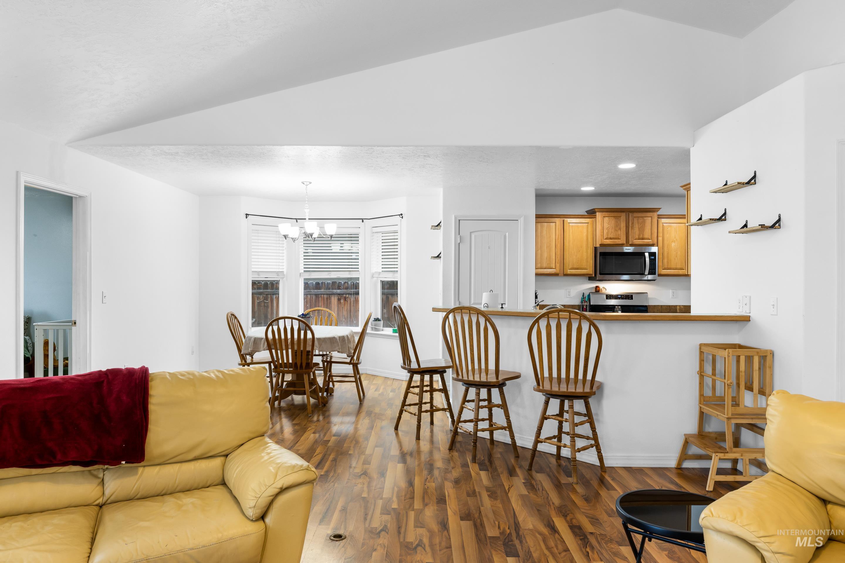 191 Southwest Quaker Drive Mountain Home, ID 83647 - Photo 12 of 43 Living area with dark wood-type flooring, vaulted ceiling, a chandelier, and recessed lighting