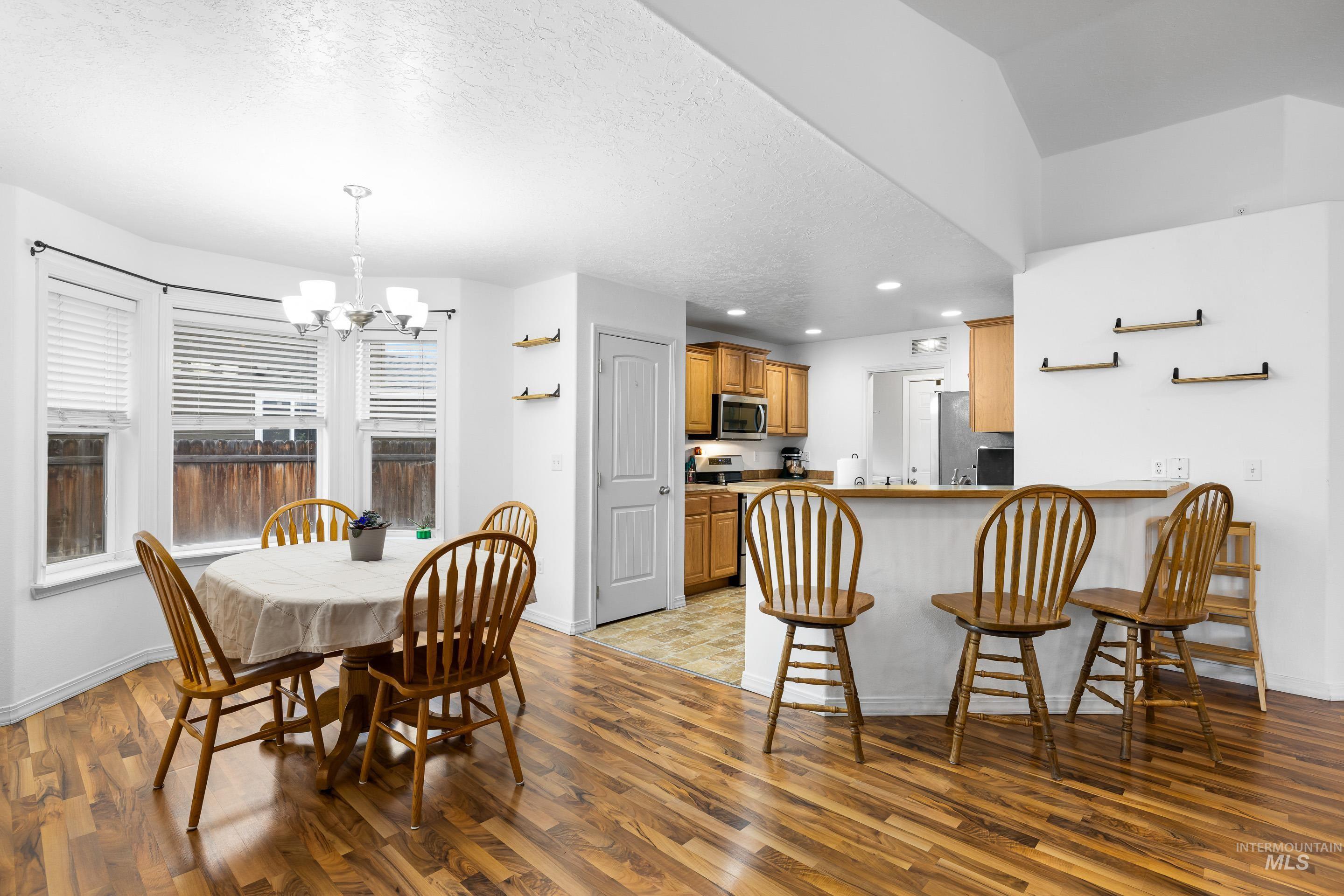191 Southwest Quaker Drive Mountain Home, ID 83647 - Photo 13 of 43 Dining area with a chandelier, light wood finished floors, a textured ceiling, and recessed lighting