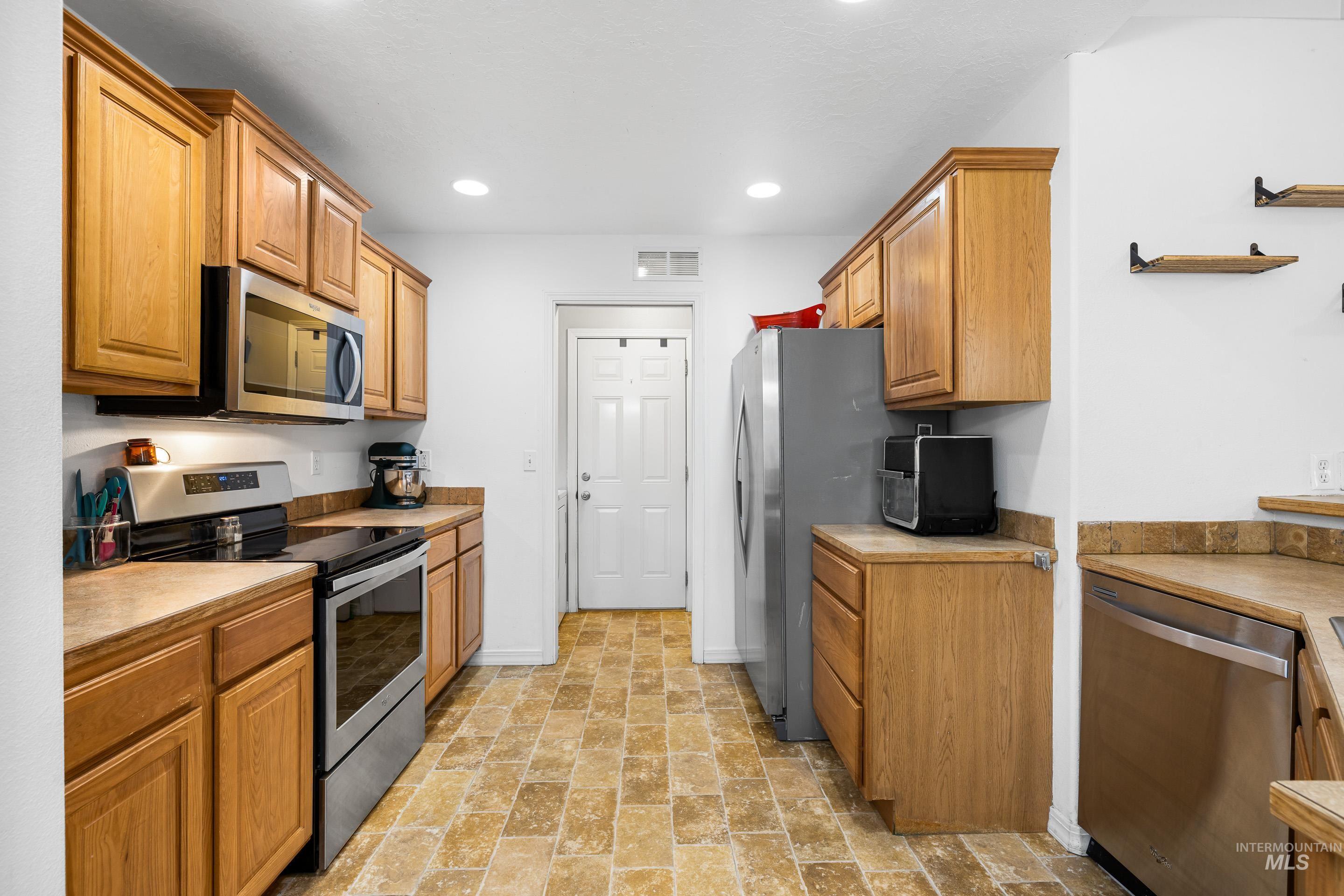 191 Southwest Quaker Drive Mountain Home, ID 83647 - Photo 17 of 43 Kitchen featuring appliances with stainless steel finishes, light countertops, brown cabinets, stone finish floors, and recessed lighting