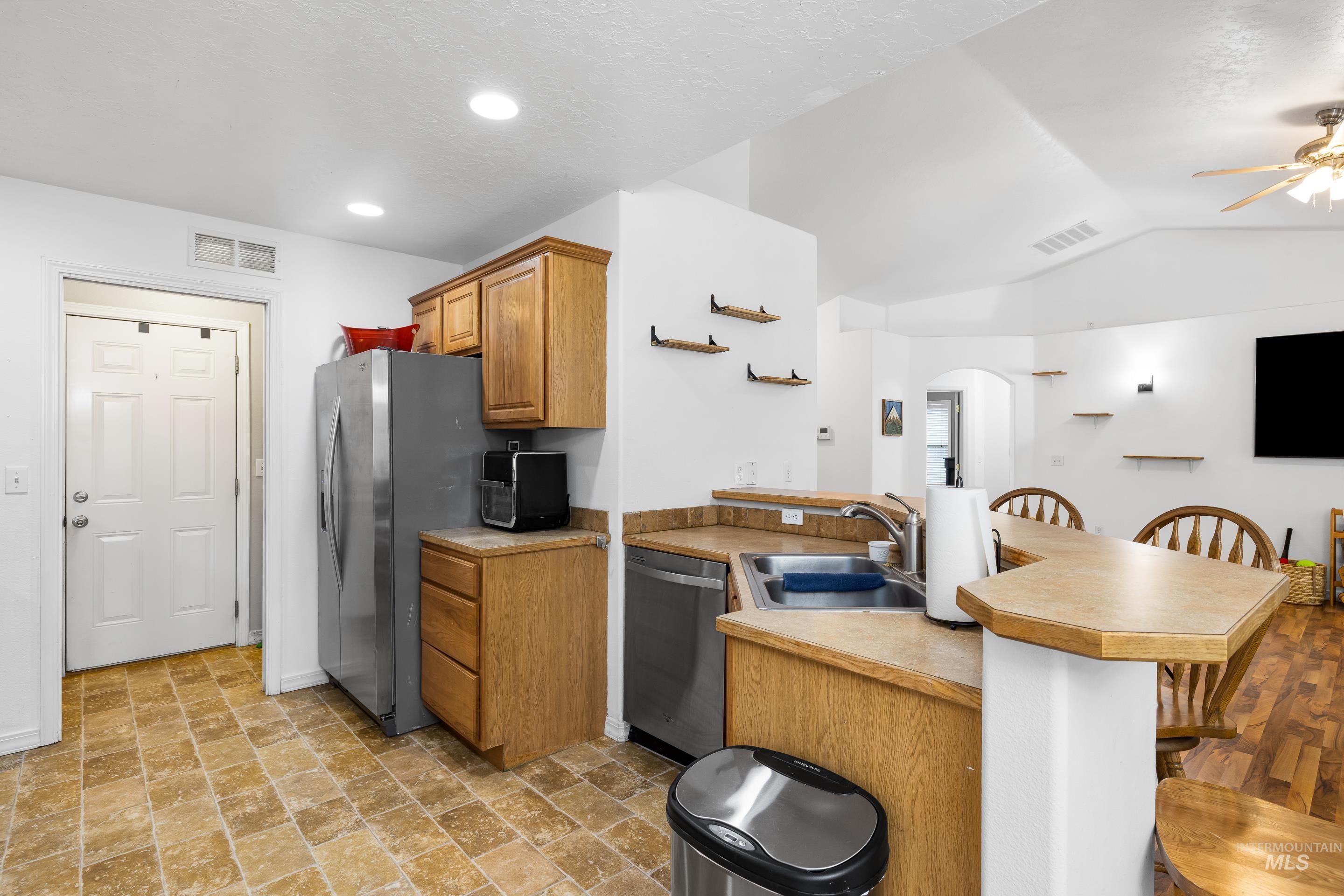 191 Southwest Quaker Drive Mountain Home, ID 83647 - Photo 18 of 43 Kitchen featuring a peninsula, arched walkways, a kitchen bar, ceiling fan, and stainless steel appliances
