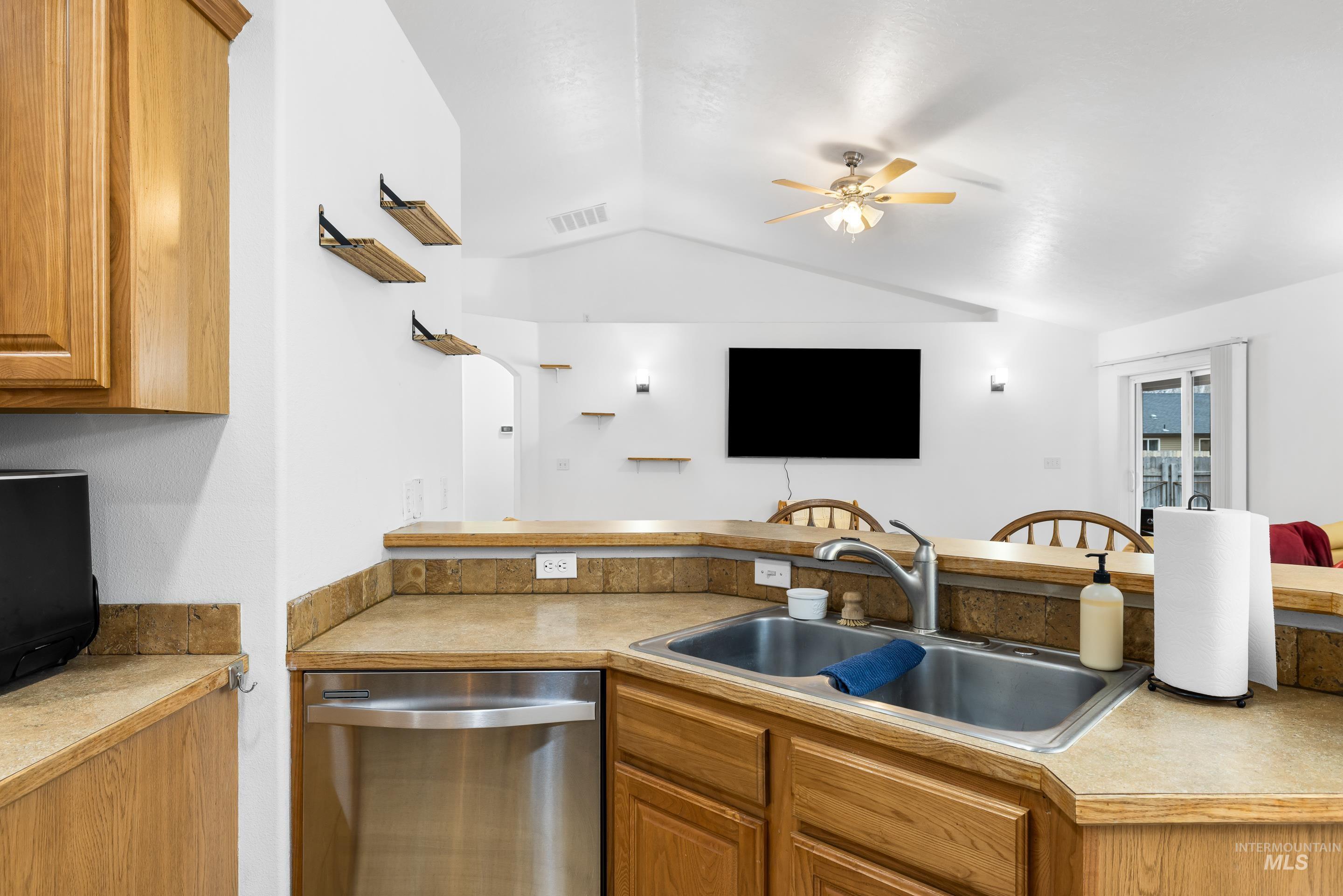 191 Southwest Quaker Drive Mountain Home, ID 83647 - Photo 20 of 43 Kitchen with dishwasher, light countertops, brown cabinetry, and lofted ceiling