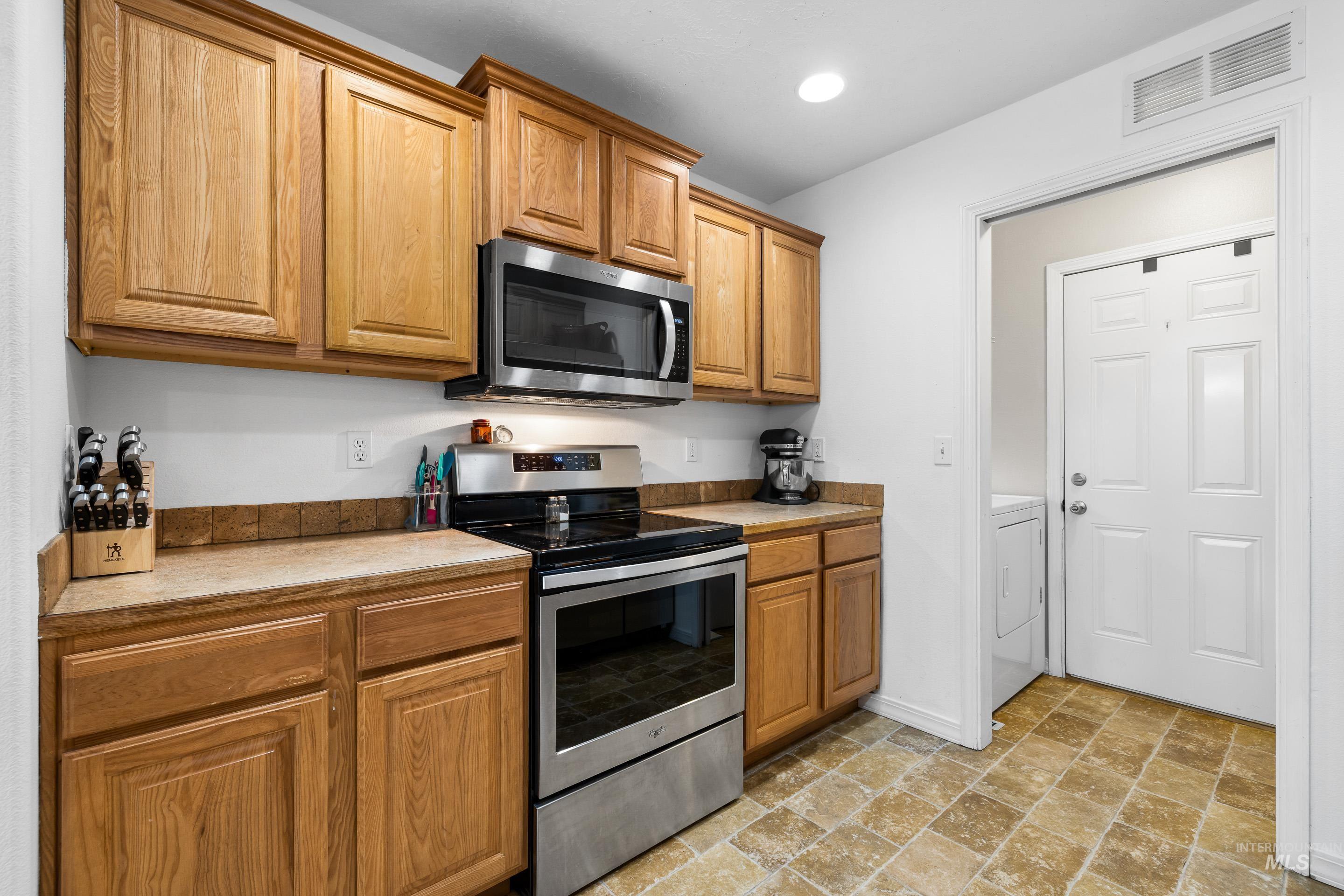191 Southwest Quaker Drive Mountain Home, ID 83647 - Photo 21 of 43 Kitchen with stainless steel appliances, stone finish flooring, light countertops, and brown cabinetry
