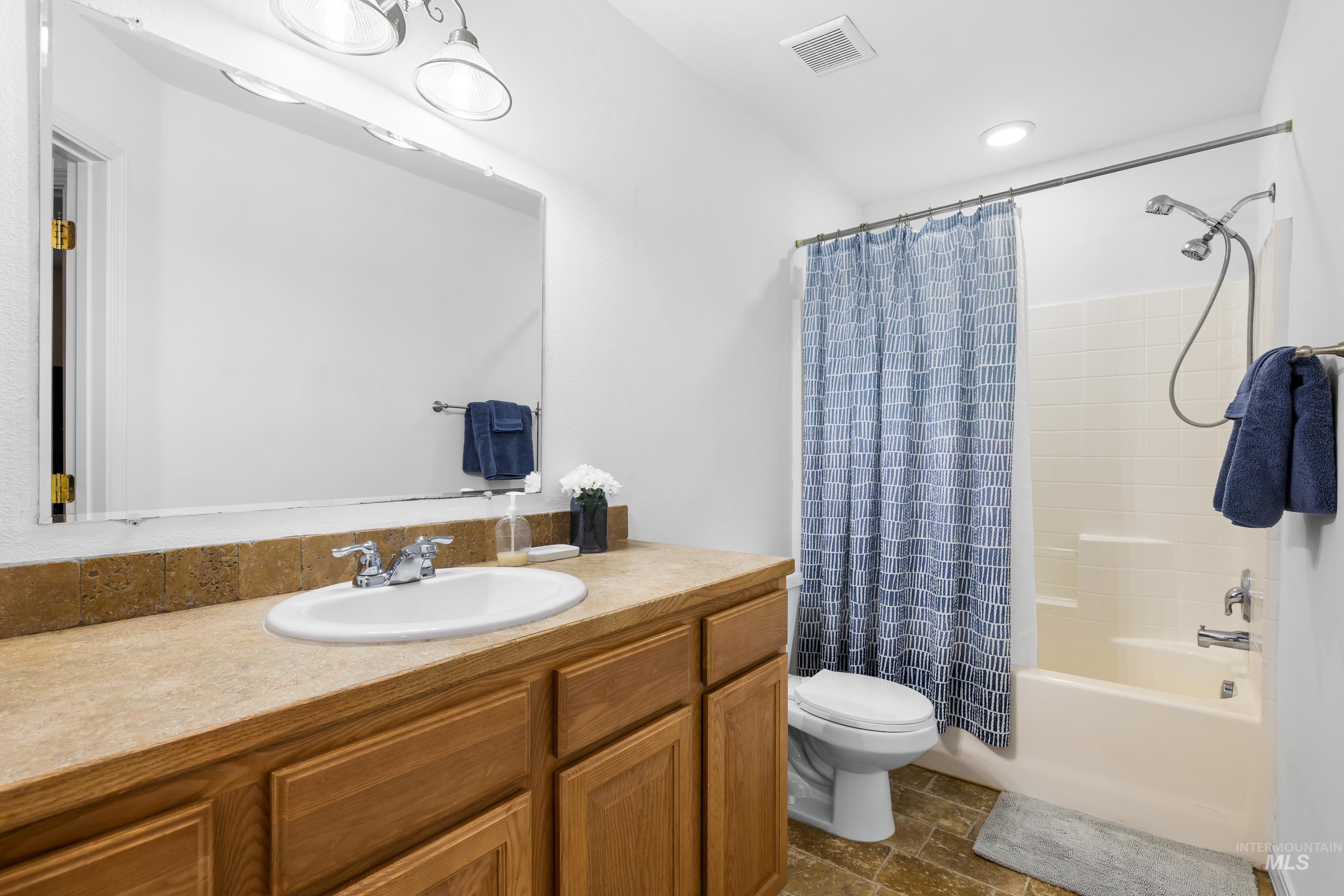191 Southwest Quaker Drive Mountain Home, ID 83647 - Photo 37 of 43 Full bath featuring vanity, shower / bath combination with curtain, and dark stone finish floors