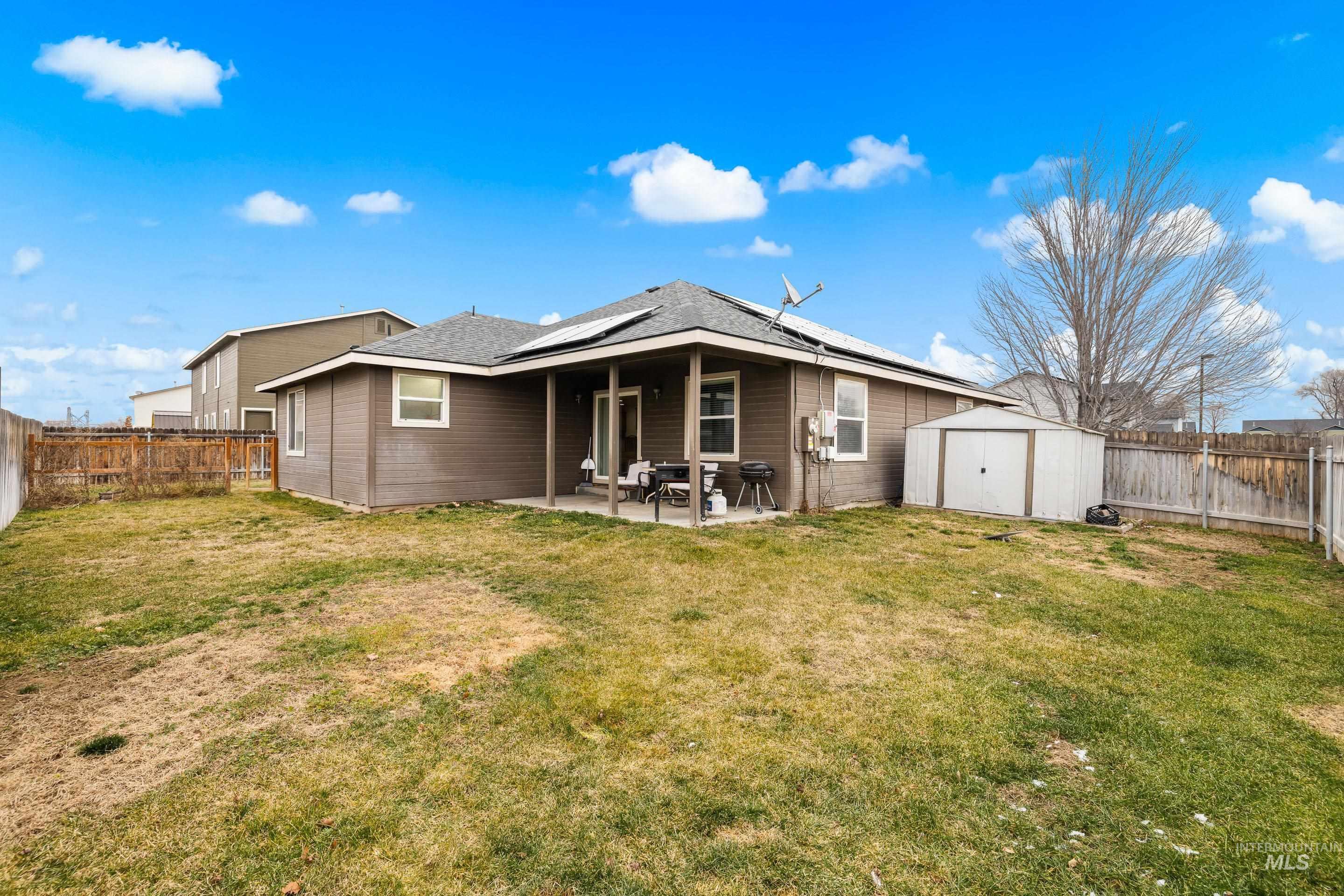 191 Southwest Quaker Drive Mountain Home, ID 83647 - Photo 42 of 43 Back of house featuring a storage shed, roof mounted solar panels, a patio, and a fenced backyard