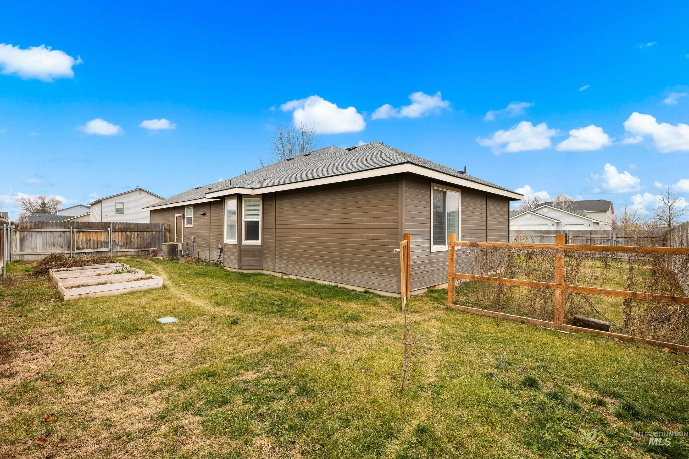191 Southwest Quaker Drive Mountain Home, ID 83647 - Photo 43 of 43 Back of house featuring a fenced backyard, a garden, and a shingled roof