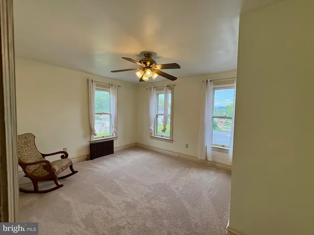 an empty room with windows and ceiling fan