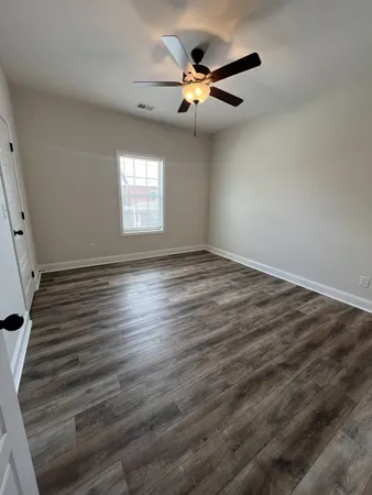 a view of a livingroom with wooden floor a ceiling fan and staircase