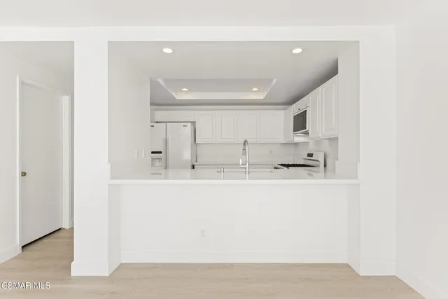 a kitchen with stainless steel appliances a stove a refrigerator a sink a white counter space and cabinets