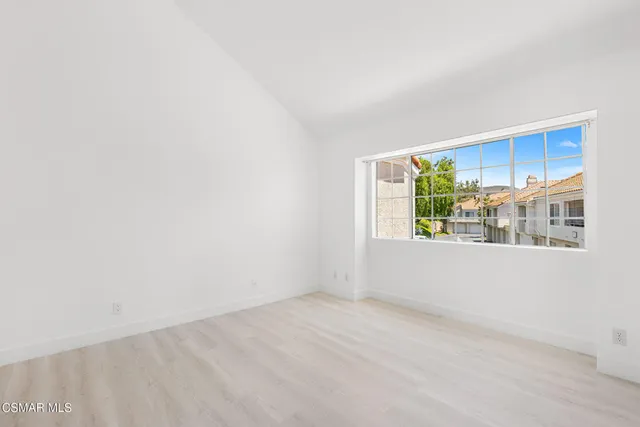 a view of an empty room with wooden floor and a bathroom