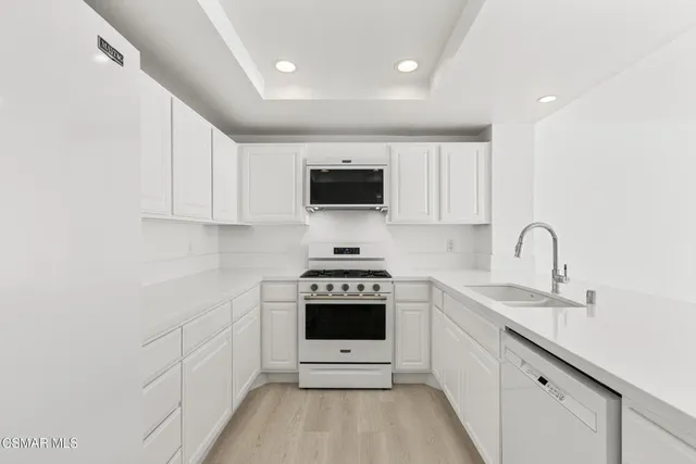 a kitchen with white cabinets a sink and appliances