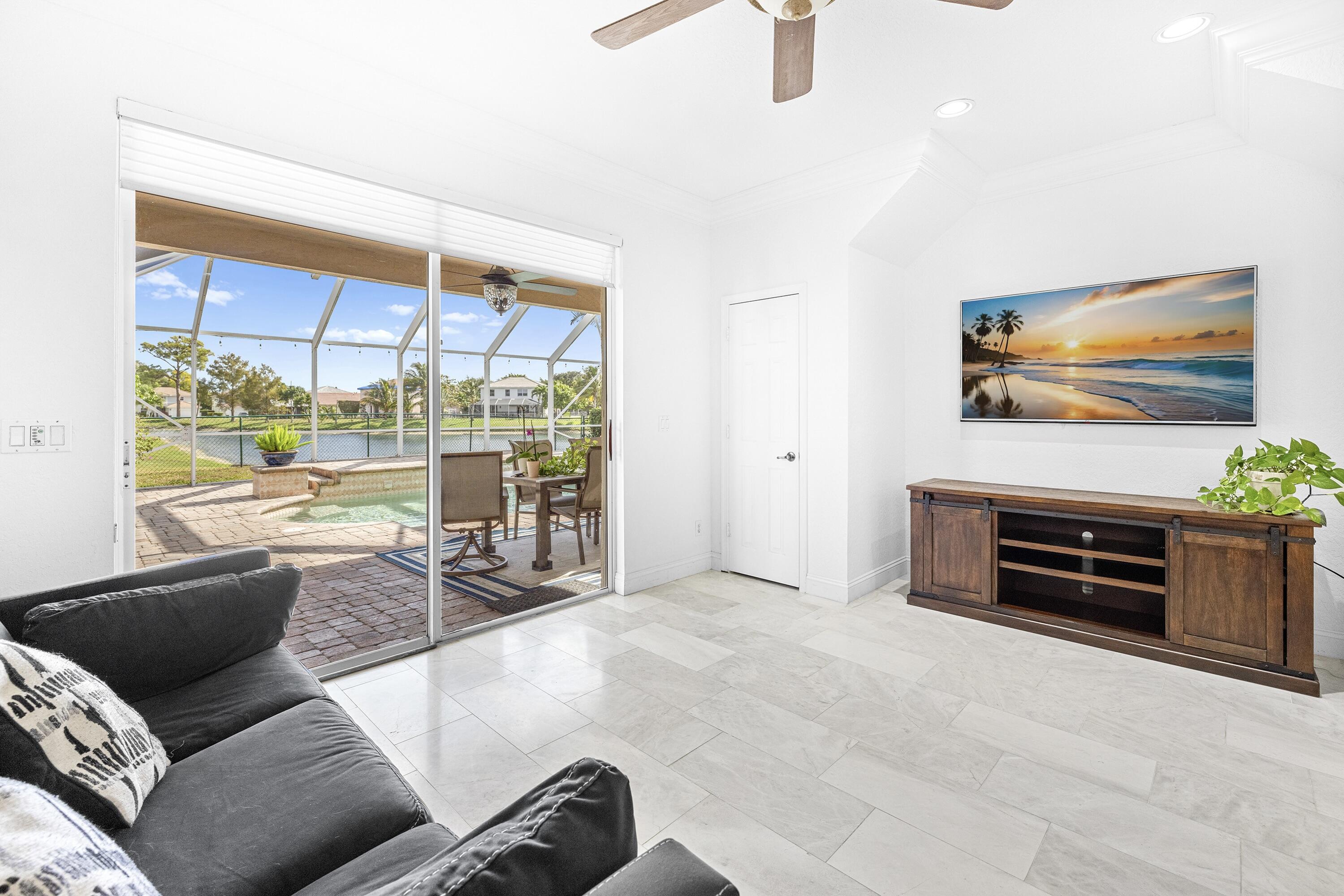 6575 Spring Meadow Drive Greenacres, FL 33413 - Photo 9 of 54 a living room with furniture a flat screen tv and floor to ceiling window