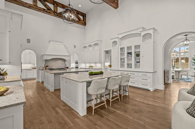 a kitchen with stainless steel appliances kitchen island granite countertop a stove a sink dishwasher and white cabinets with wooden floor