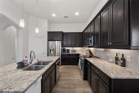 a kitchen with stainless steel appliances granite countertop a sink a stove and a refrigerator