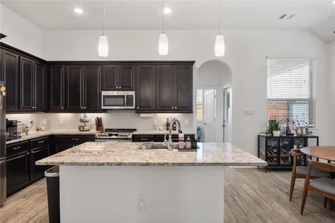 a kitchen with granite countertop a sink a counter space appliances and cabinets