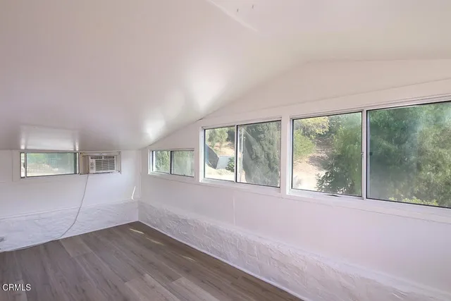 a view of a big room with wooden floor and windows