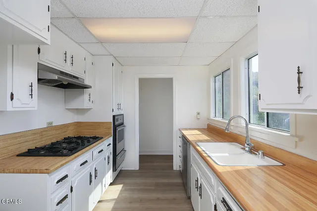 a kitchen with granite countertop stainless steel appliances a sink stove and cabinets