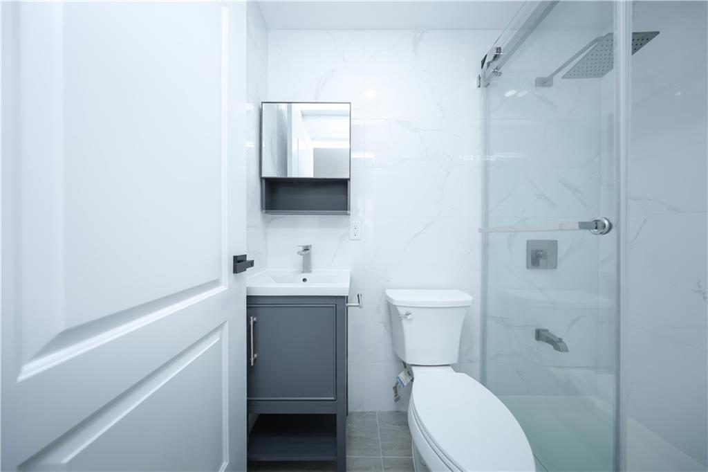 1725 68th Street, Unit 3F Brooklyn, NY 11204 - Photo 9 of 19 a bathroom with a toilet a sink a mirror and vanity