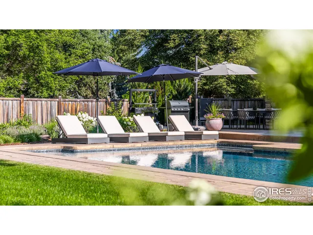 a view of swimming pool with a table and chairs under an umbrella