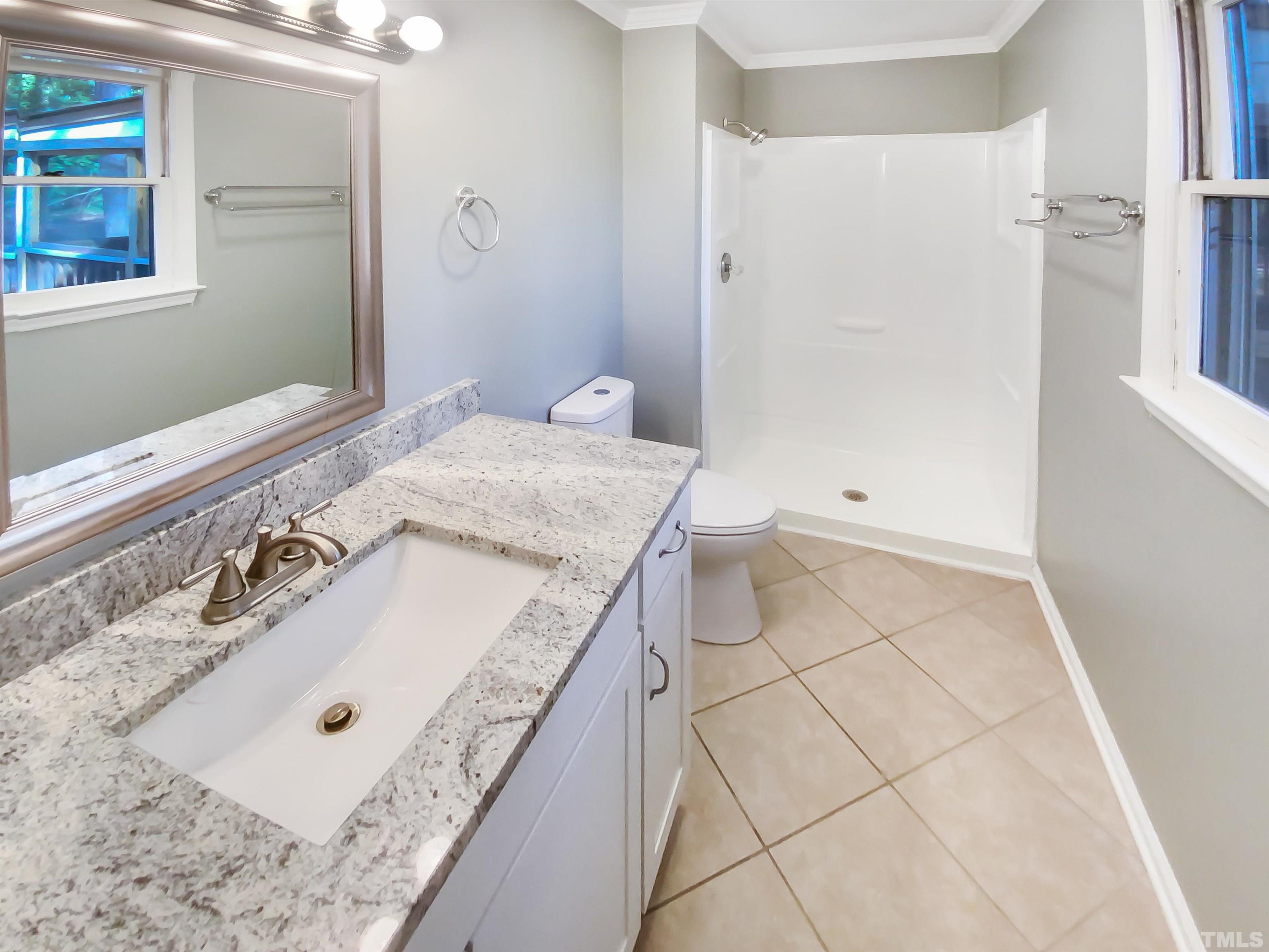 6920 Glendower Road Raleigh, NC 27613 - Photo 25 of 32 a bathroom with a granite countertop sink a mirror and a bathtub