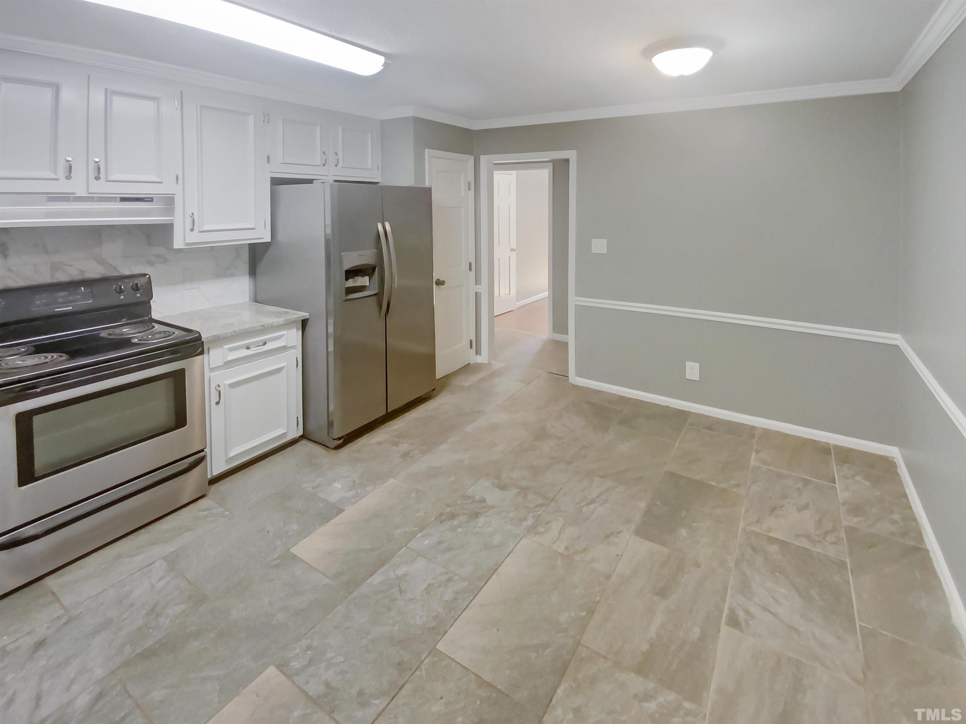 6920 Glendower Road Raleigh, NC 27613 - Photo 6 of 32 a view of a kitchen with refrigerator and white cabinets