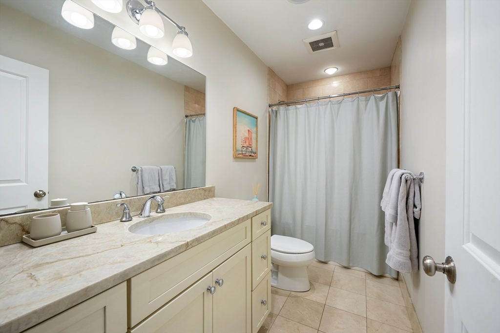 861 East 2nd Street, Unit 1 Boston, MA 02127 - Photo 19 of 30 a bathroom with a granite countertop sink a toilet and a mirror
