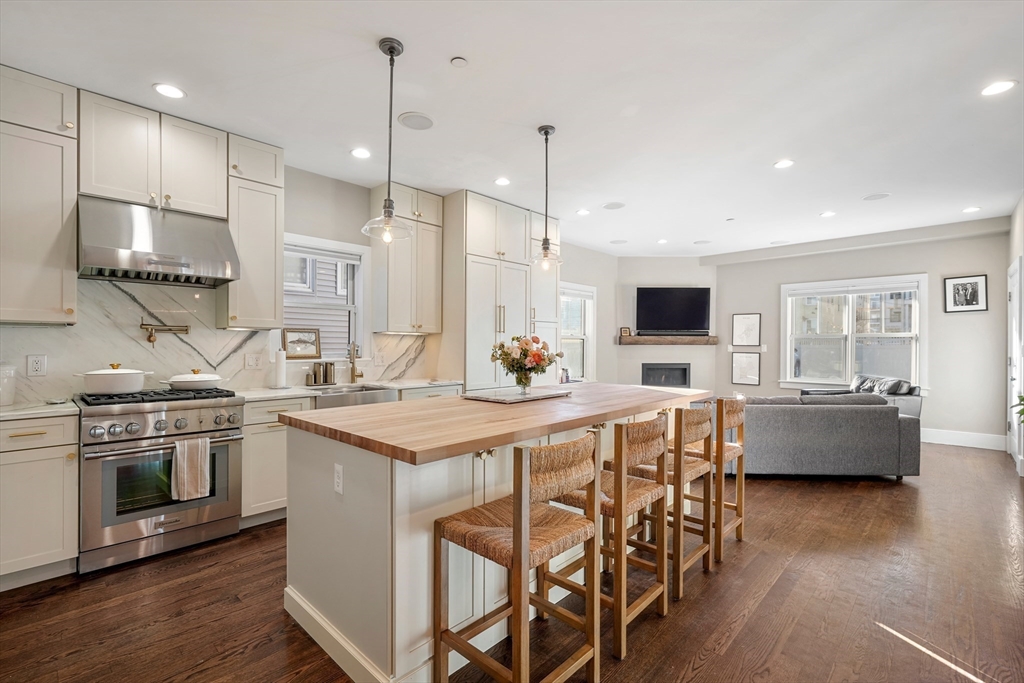 861 East 2nd Street, Unit 1 Boston, MA 02127 - Photo 2 of 30 a kitchen with stainless steel appliances kitchen island granite countertop a stove a sink a dining table and chairs with wooden floor
