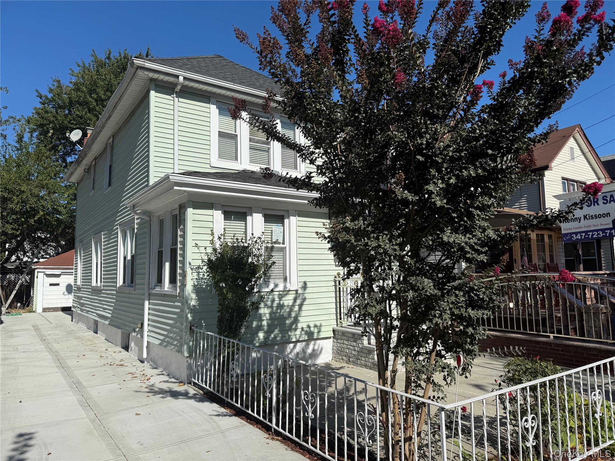 a view of a house with a small yard and a large tree