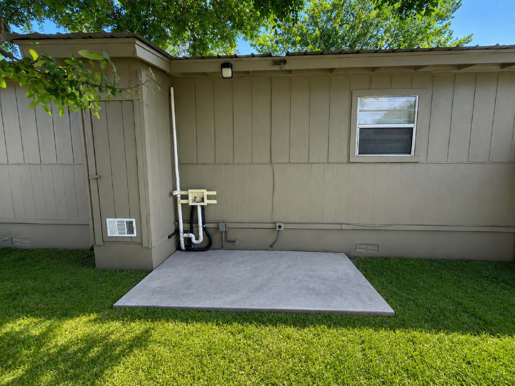 610 Gunter Street Austin, TX 78702 - Photo 14 of 16 A well-maintained side yard features a small concrete patio, ideal for outdoor enjoyment.
