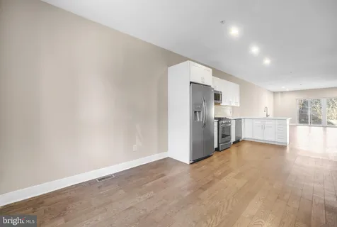 a view of a kitchen with refrigerator and white cabinets