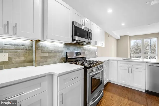 a kitchen with stainless steel appliances granite countertop a sink and a stove top oven