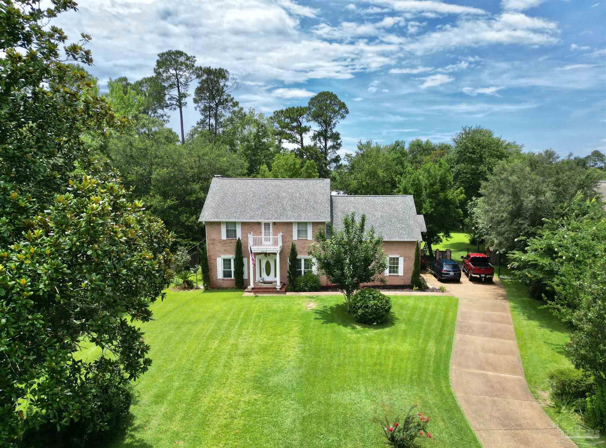 a view of a house with a big yard plants and large trees