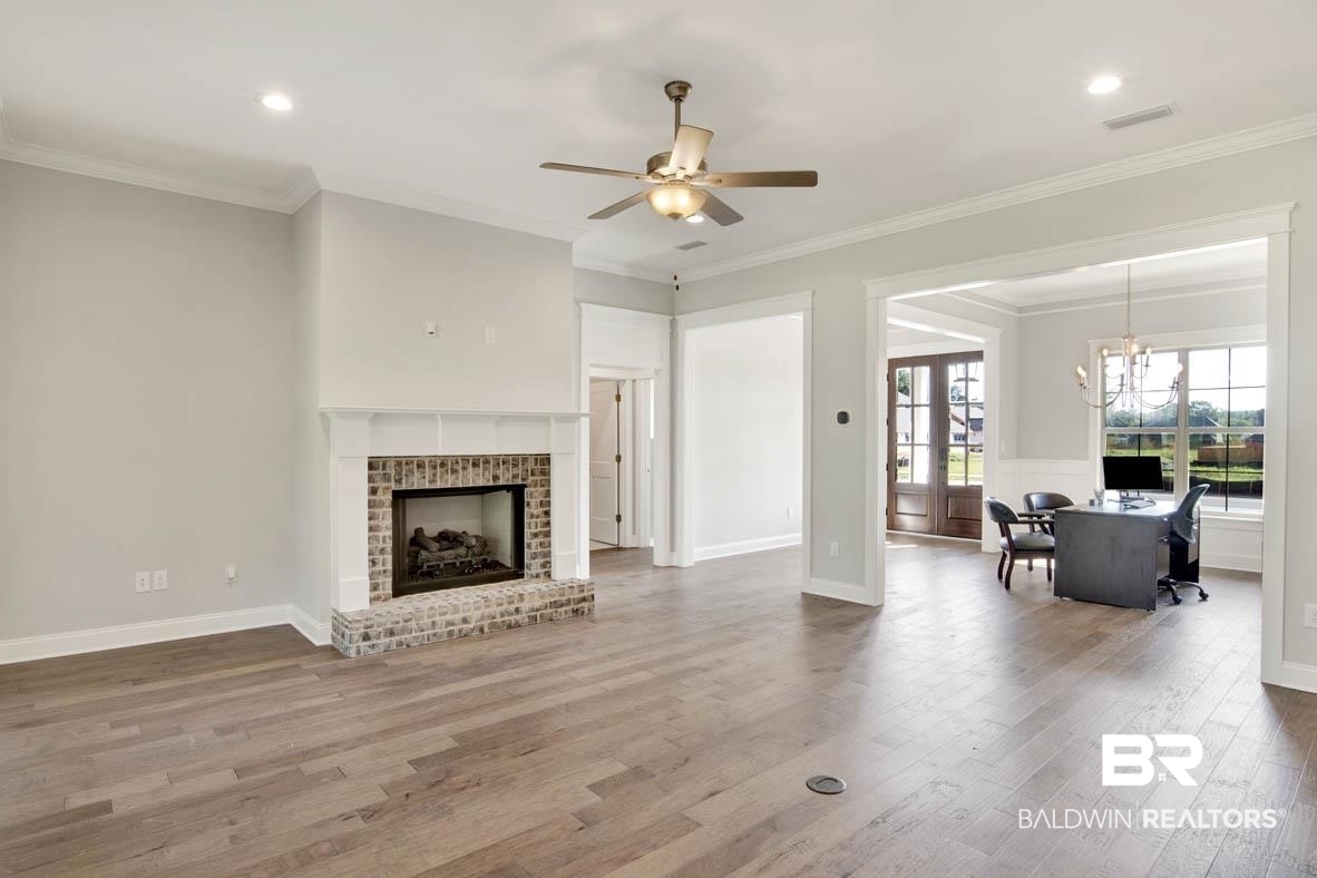393 Garrison Boulevard Fairhope, AL 36532 - Photo 6 of 40 Living room featuring ceiling fan with notable chandelier, crown molding, a brick fireplace, and hardwood / wood-style floors