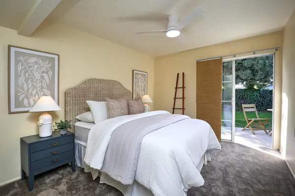 a spacious bedroom with a bed and a lamp on dresser